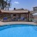 a pool with chairs and umbrellas by a house